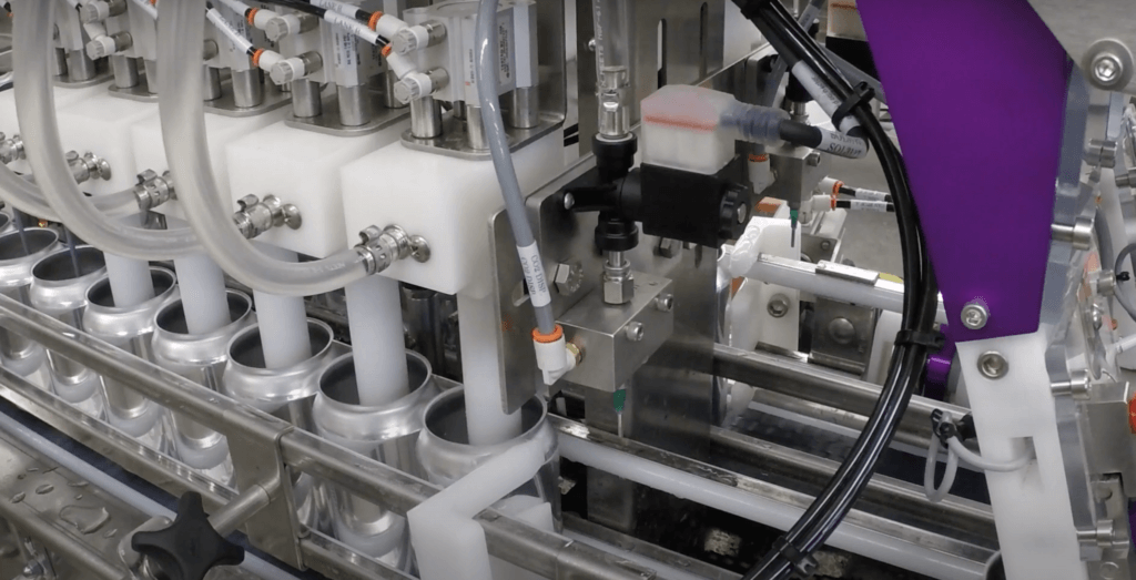 Close up view of aluminum cans being filled by a Twin Monkeys canning system