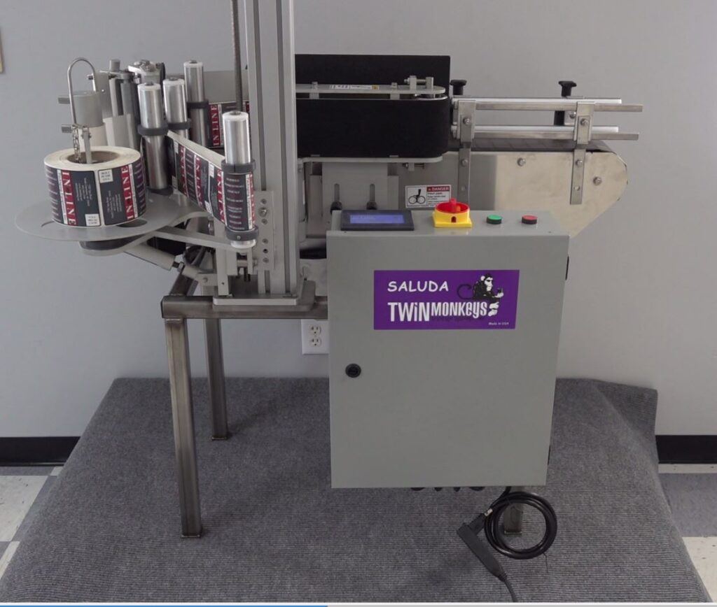 can labeling machine with a purple Twin Monkeys logo sticker on it.